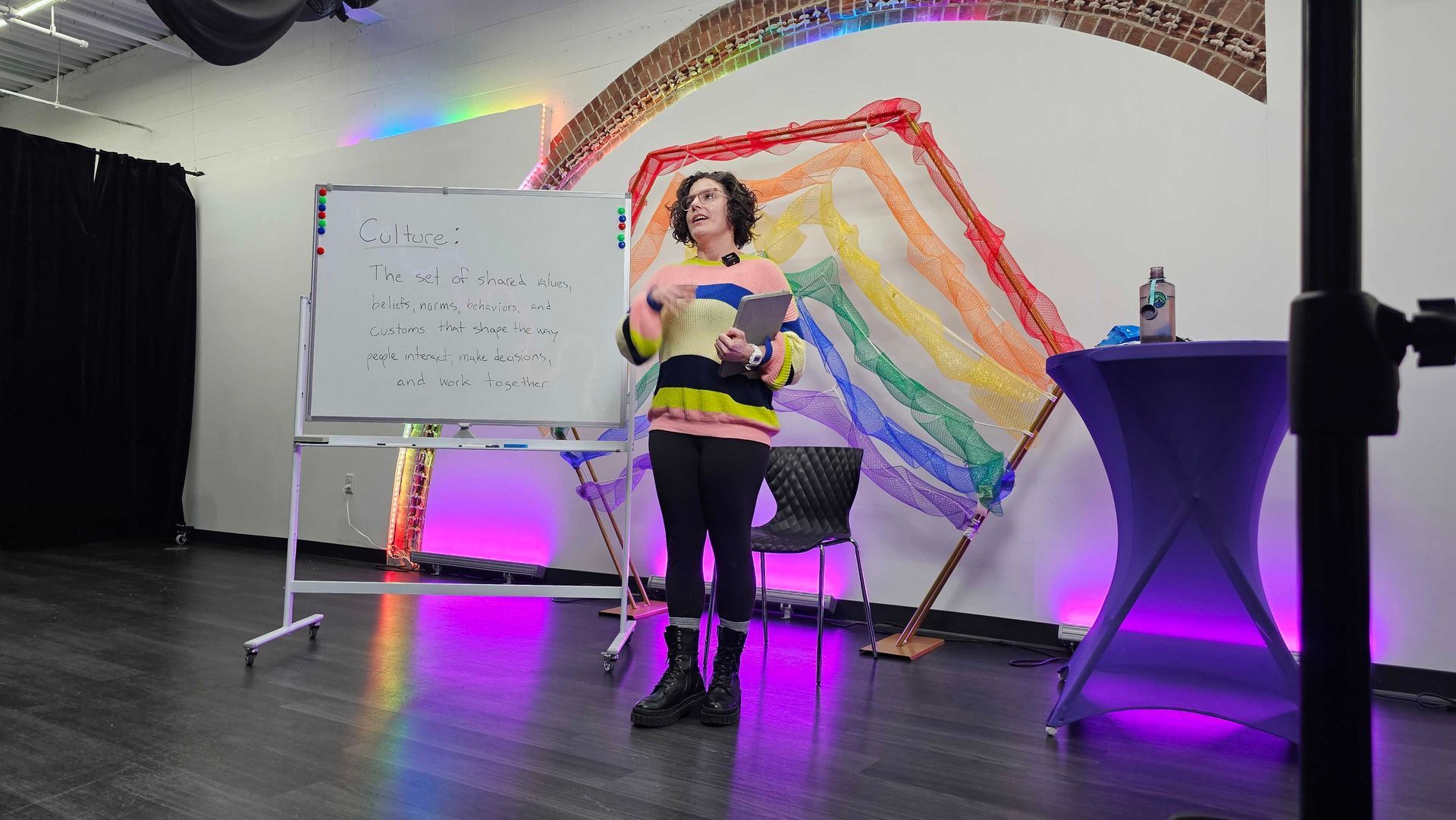 Person standing by a whiteboard giving a presentation in a room decorated with a rainbow.