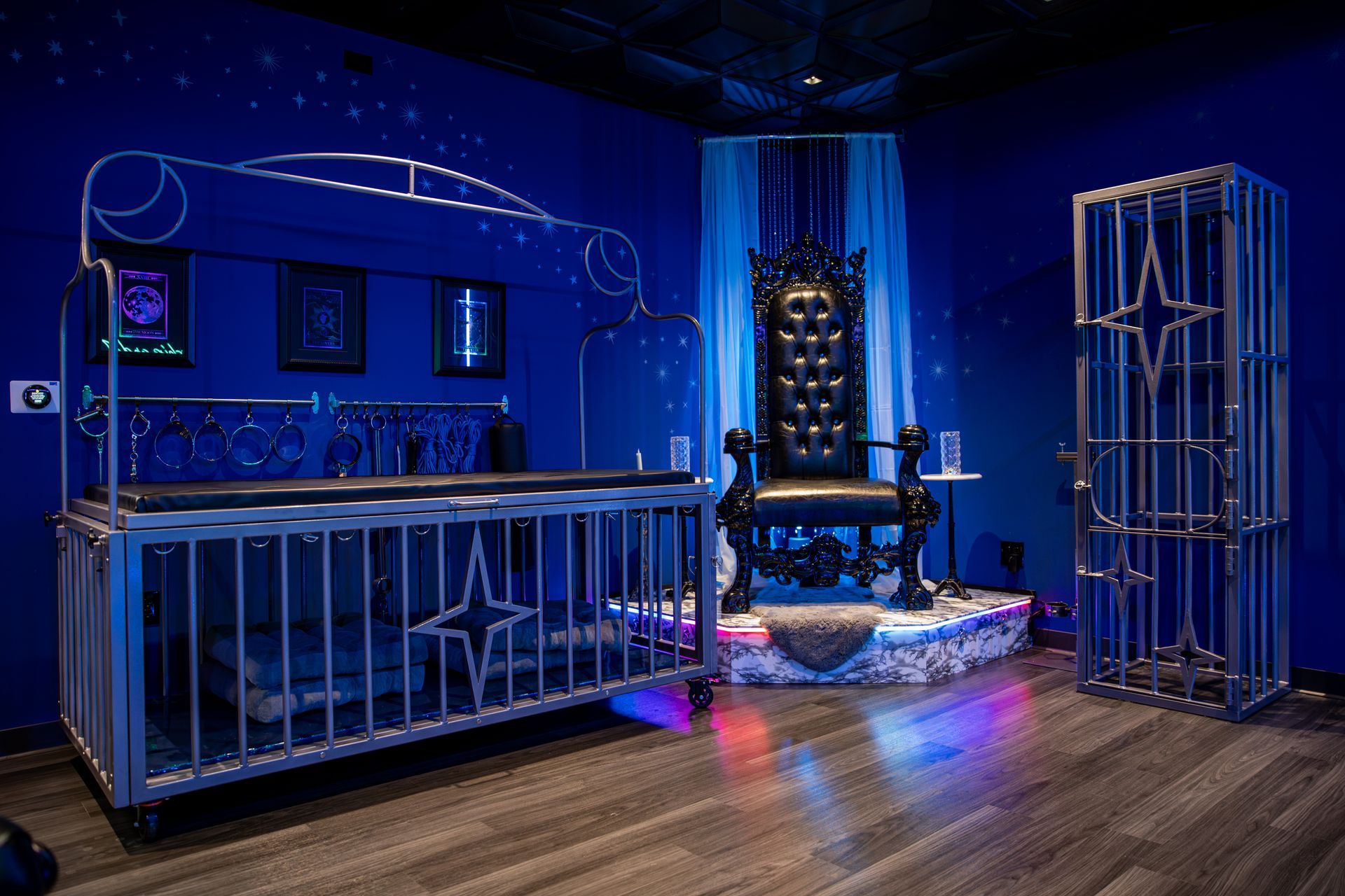 Blue-lit room with metal bed and cage, a throne, and a cage-like structure. Stars are on the walls.
