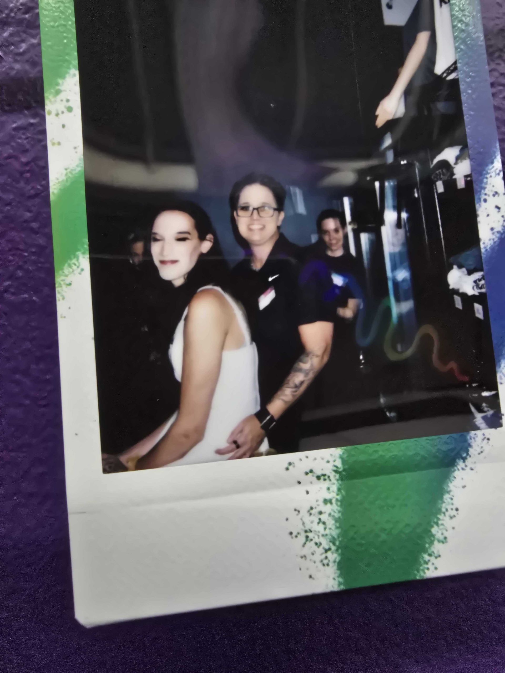 Woman in white dress with arm around another person in black shirt; party setting.