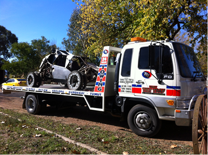 A white SUV is being towed down a highway by a tow truck.