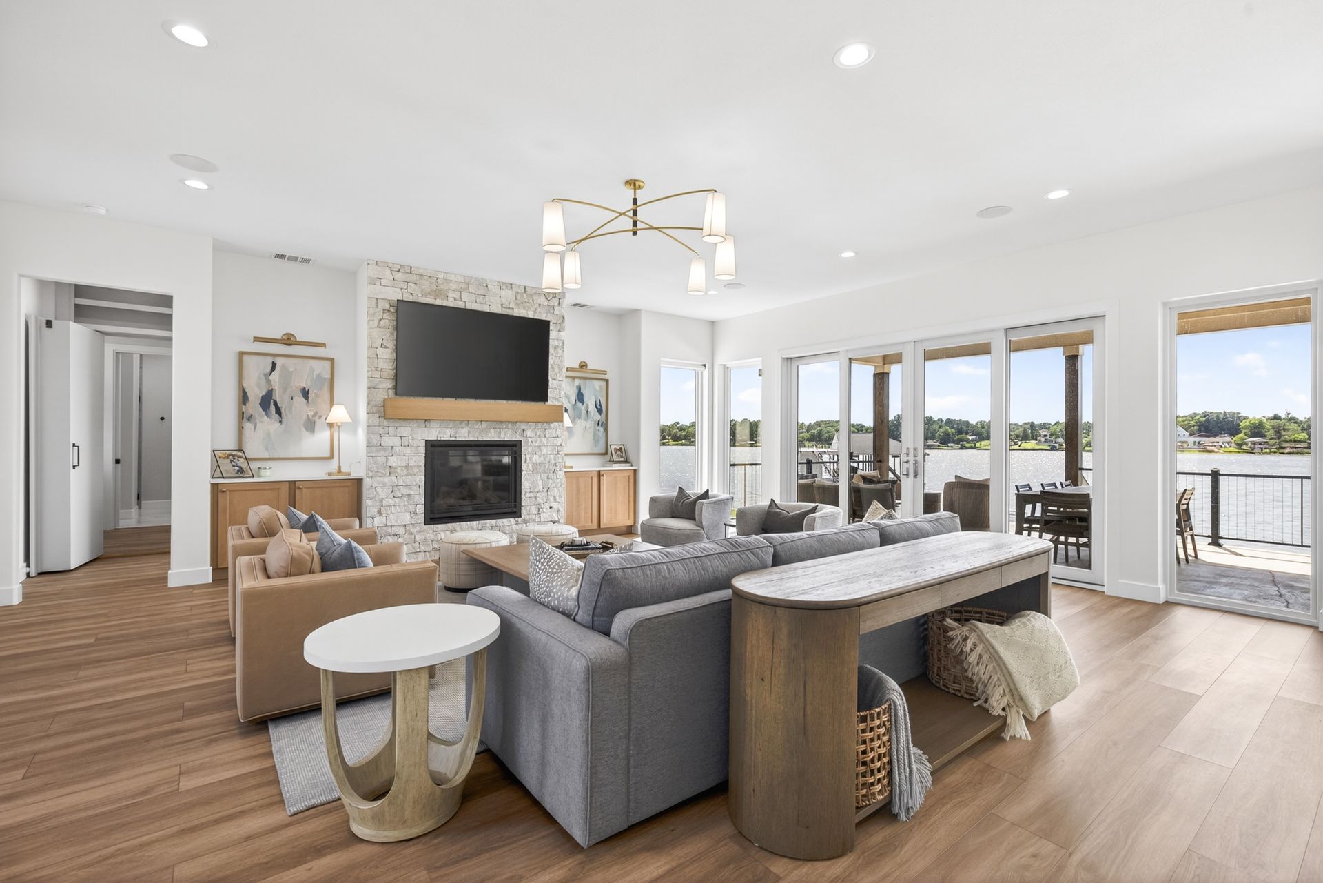 Bright open living room with gray sofas, fireplace, chandelier, and ocean-view windows