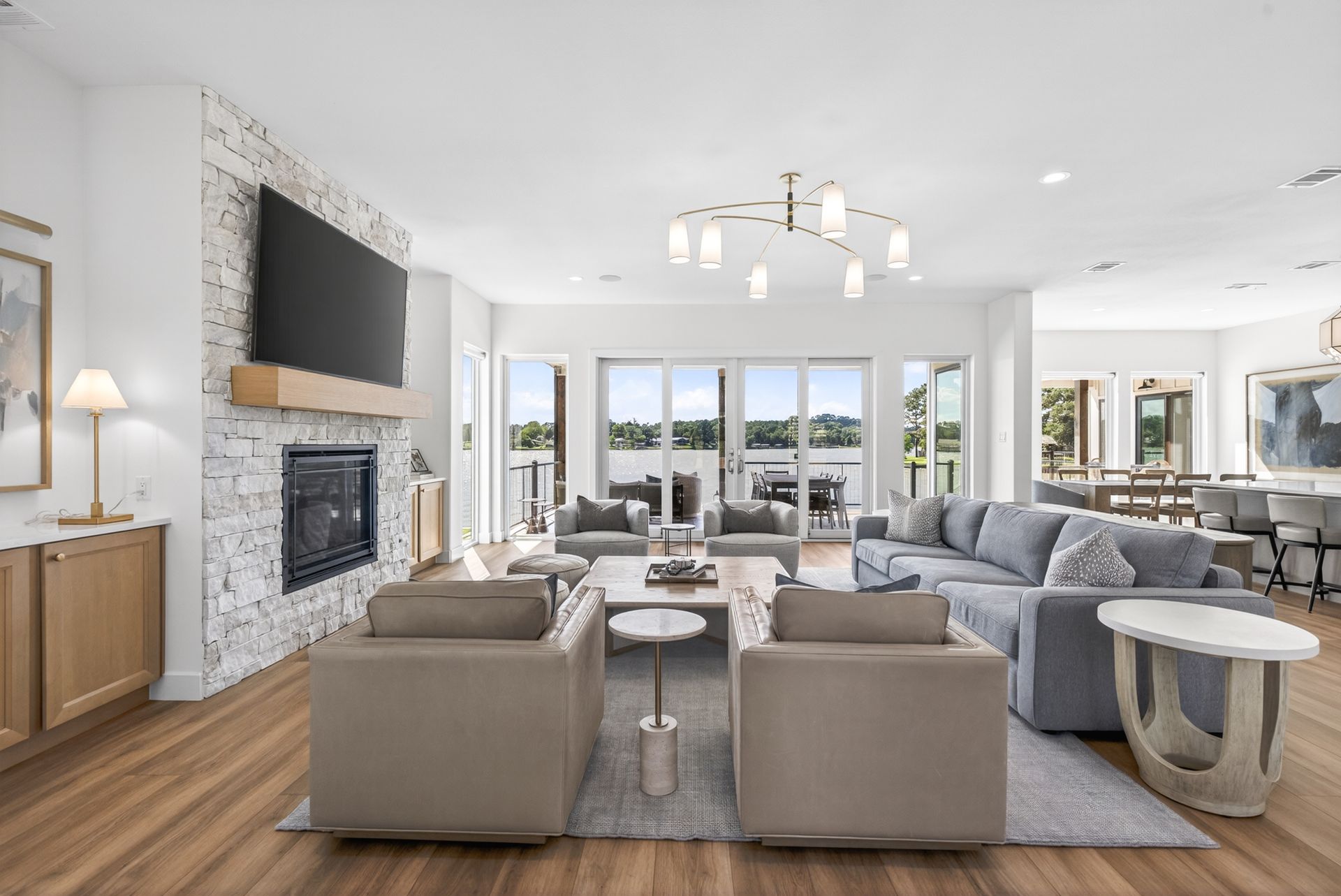 Bright open living room with gray sofas, fireplace, large windows, and wood floors