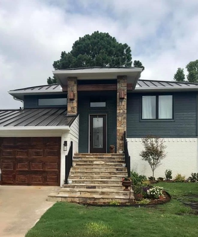 A large house with stairs leading up to the front door and a large garage.
