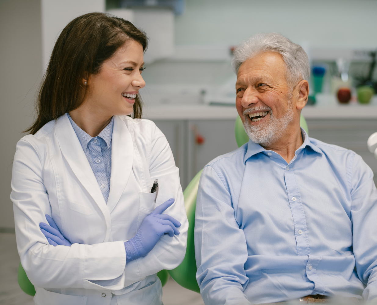 Two people in lab coats smiling and talking in a bright clinical office