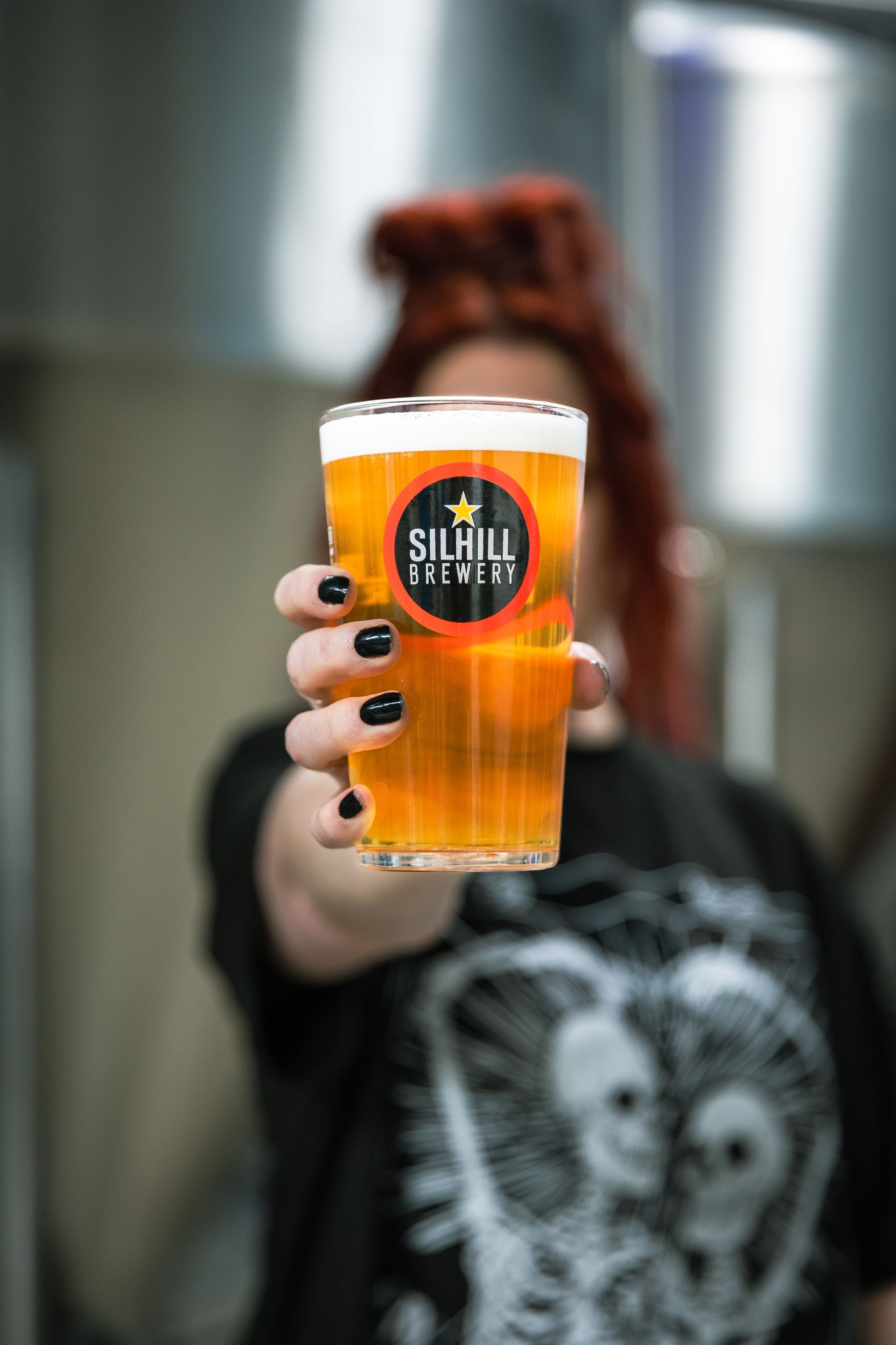 A woman is holding a glass of beer that says silvilla brewing