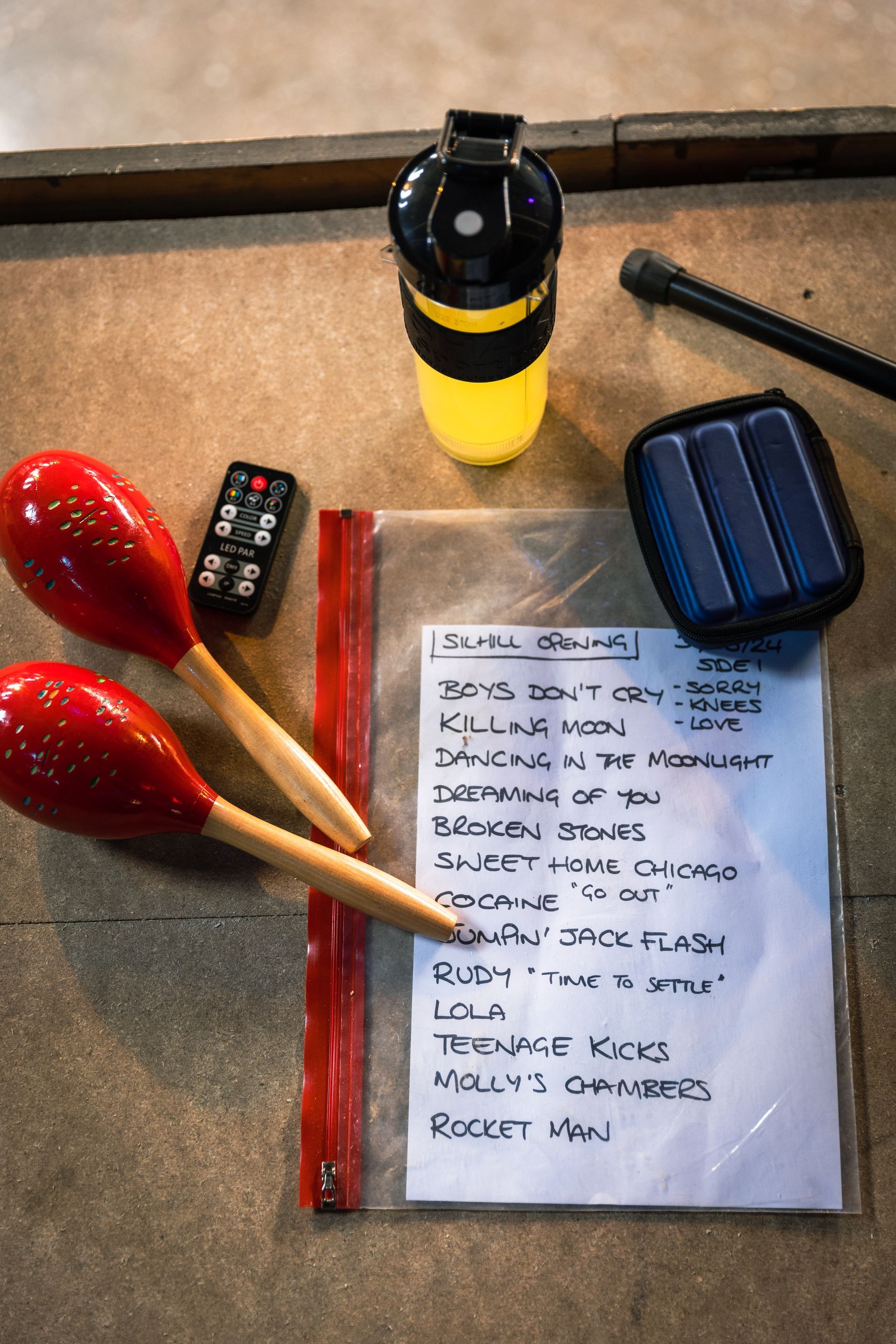 A list of items on a table including maracas and a remote control