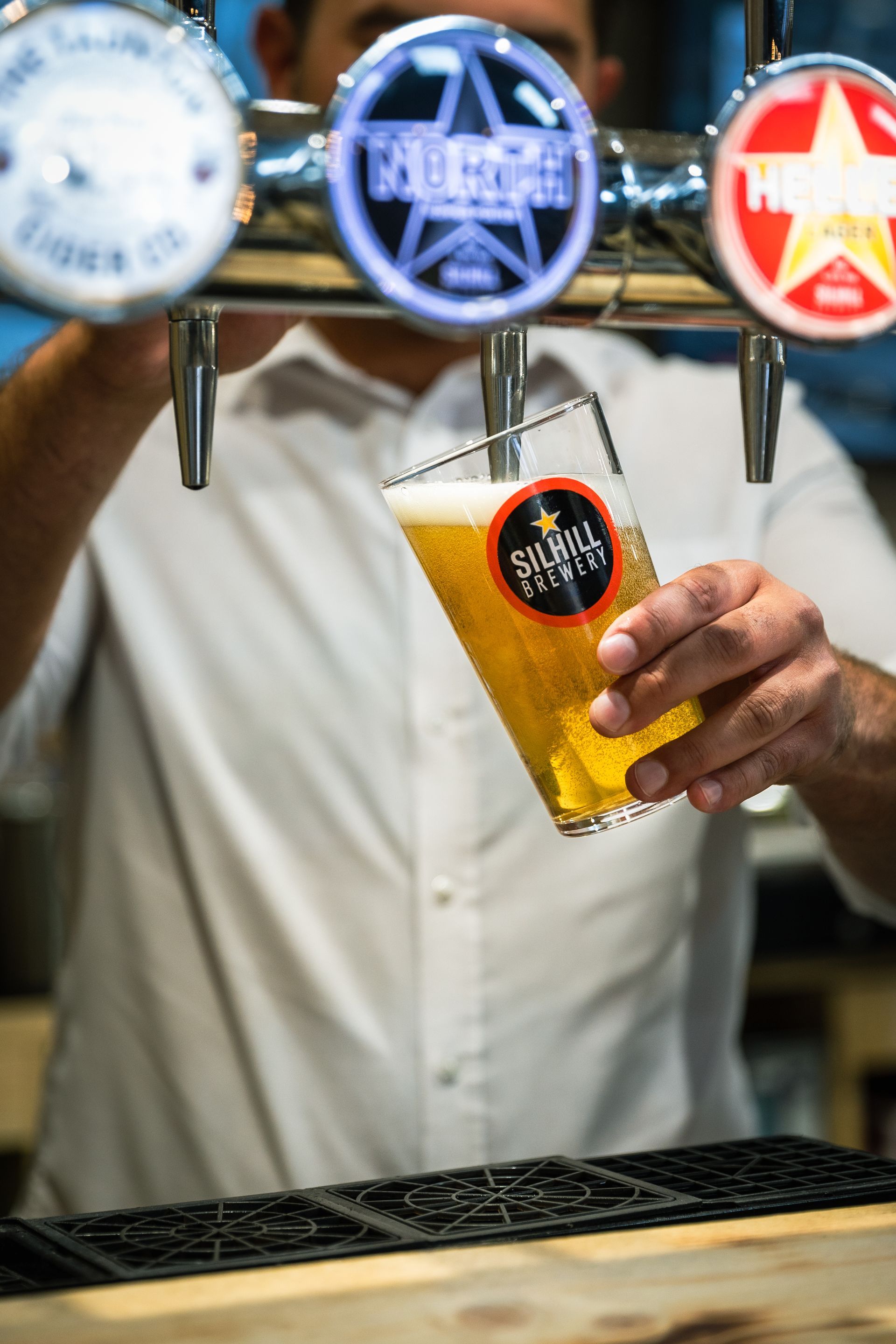 A man is pouring a glass of beer from a tap