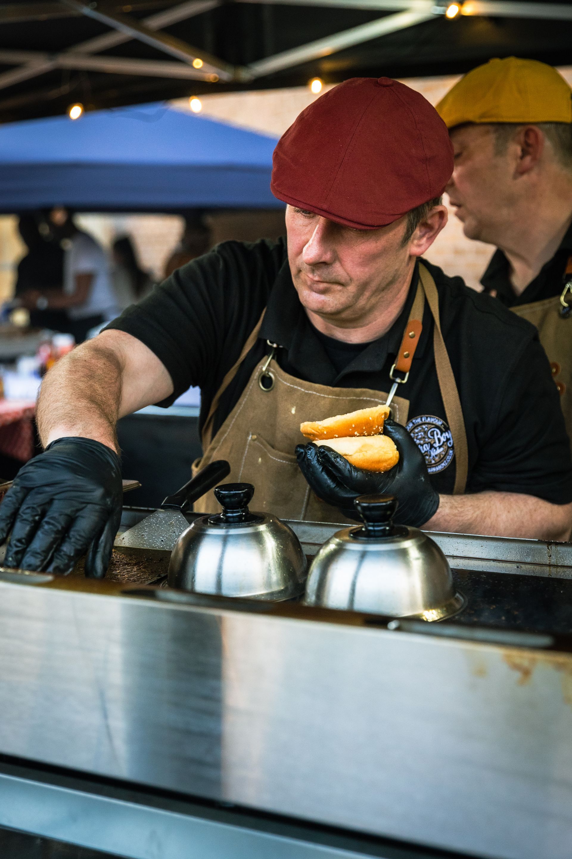 A man wearing a red hat is cooking food on a grill.