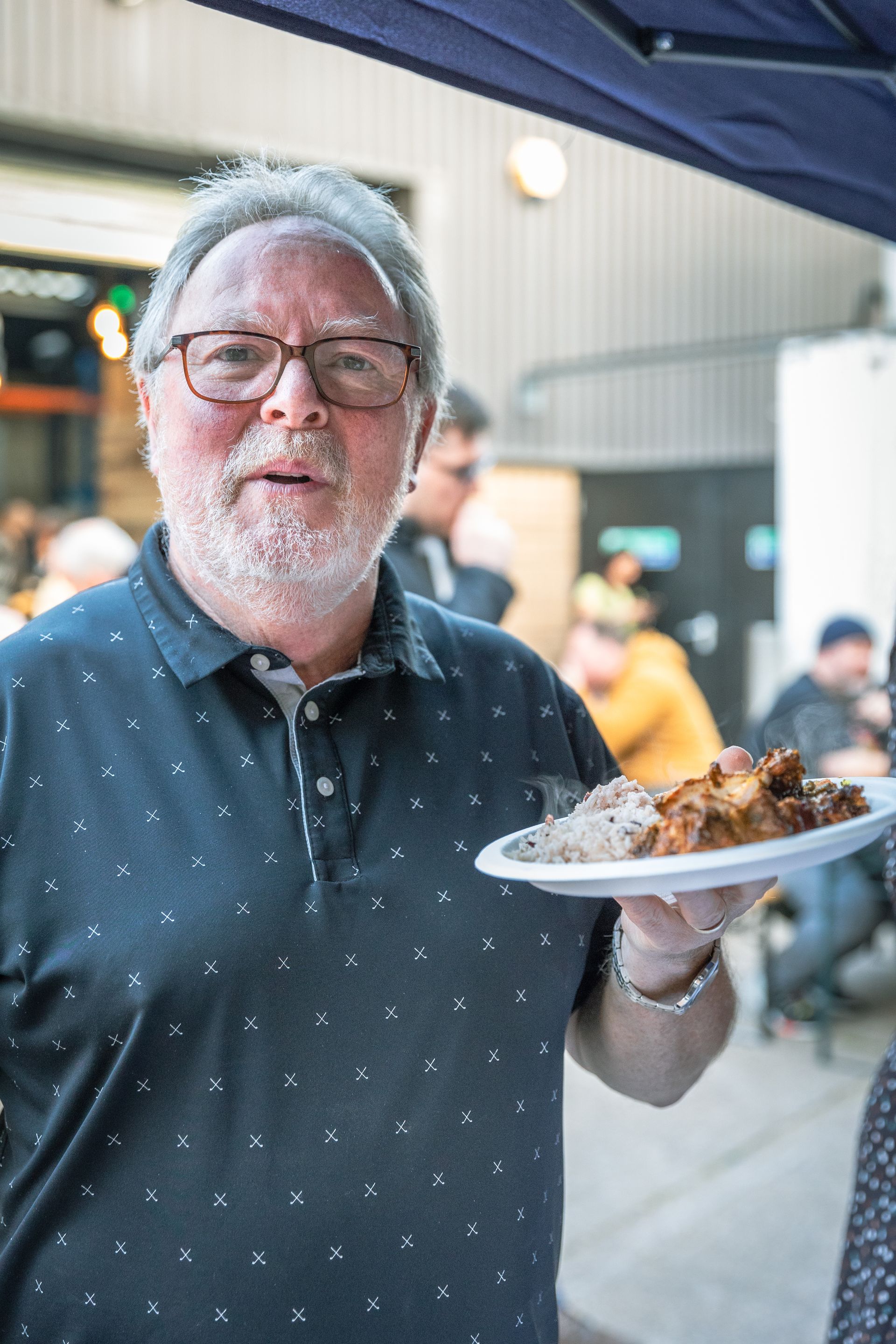 A man is holding a plate of food in his hand.