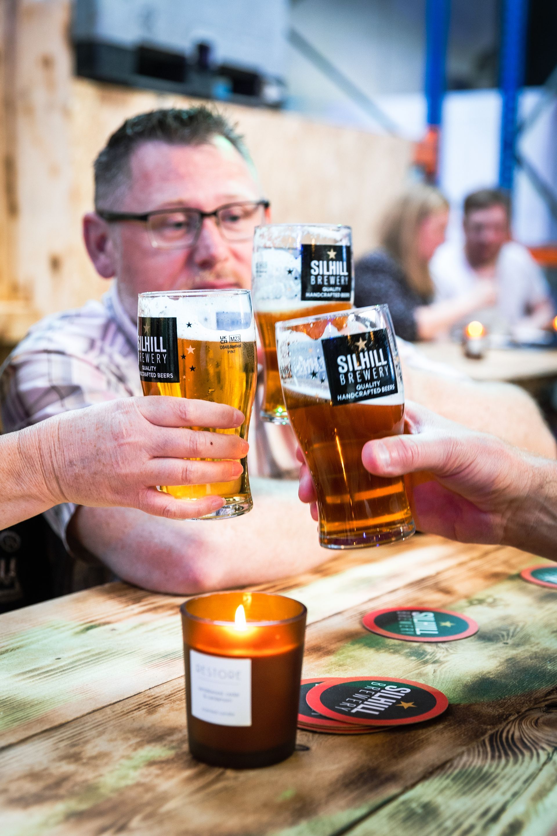 A group of people are sitting at a table toasting with beer glasses.