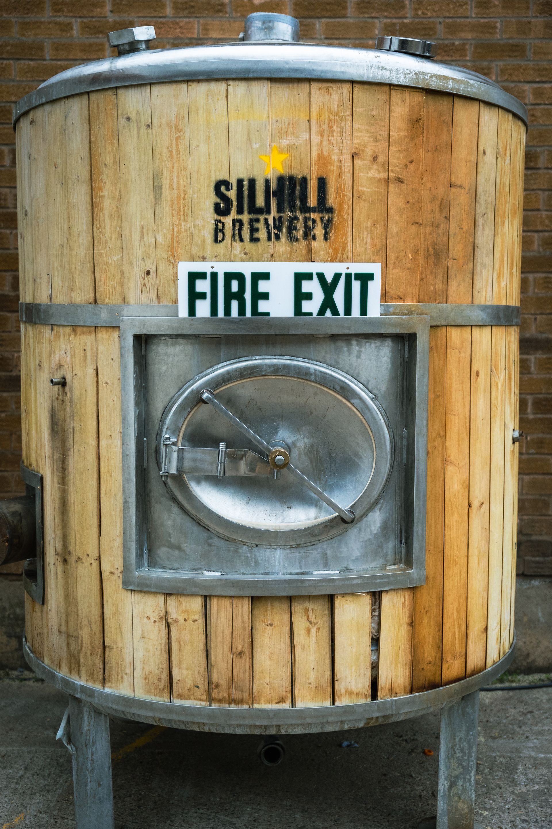 A wooden barrel with a sign that says fire exit