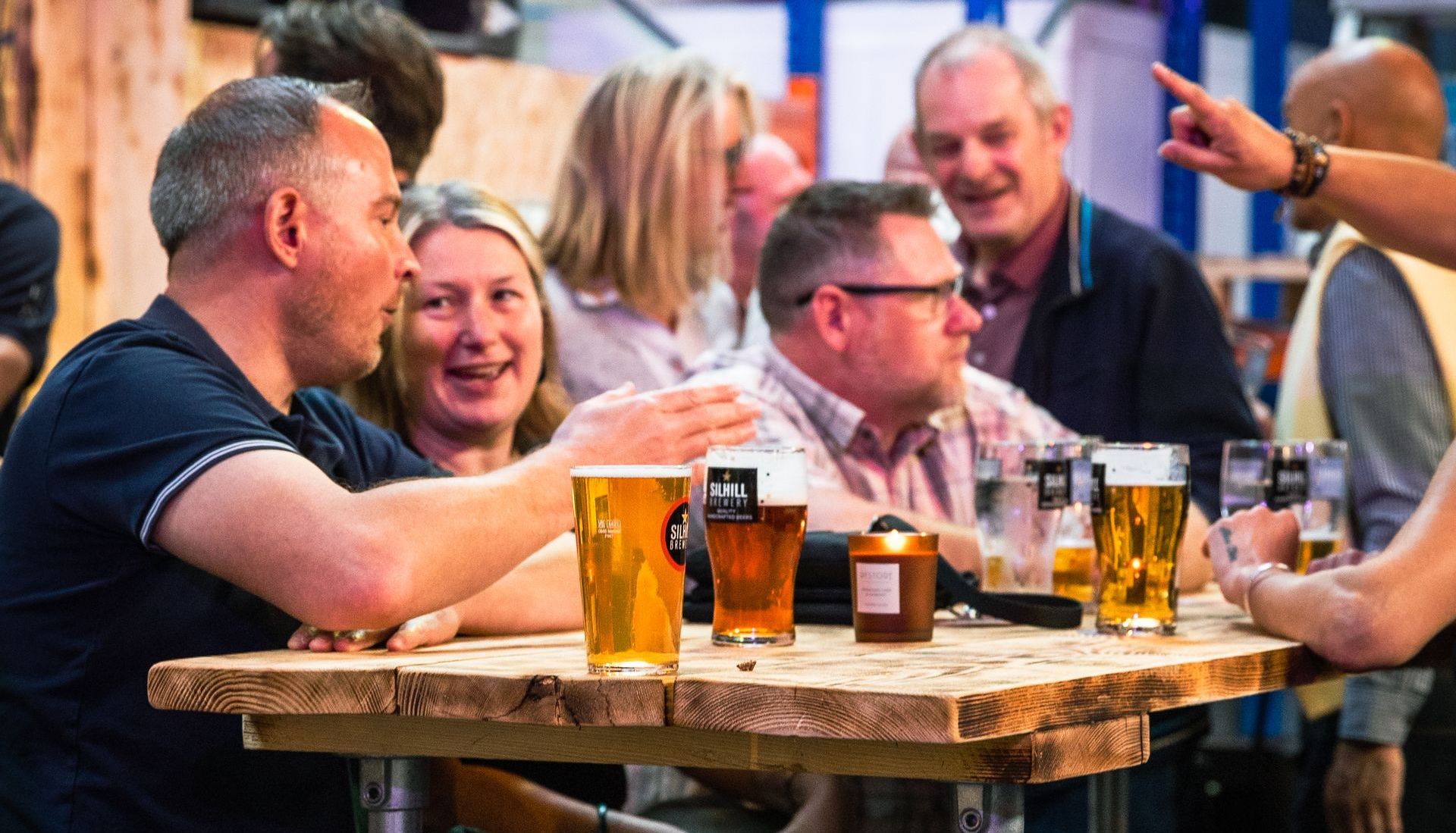 A group of people are sitting at a table drinking beer.