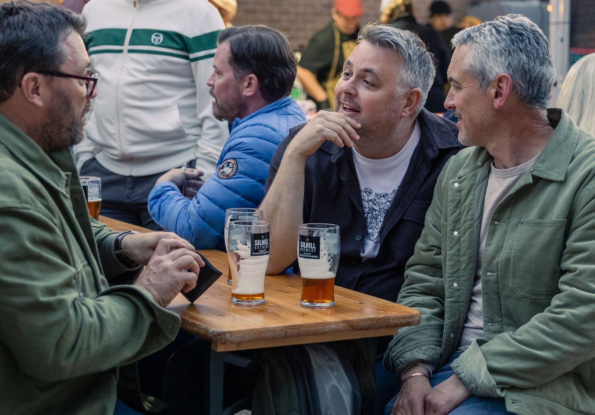 A group of men are sitting at a table drinking beer.