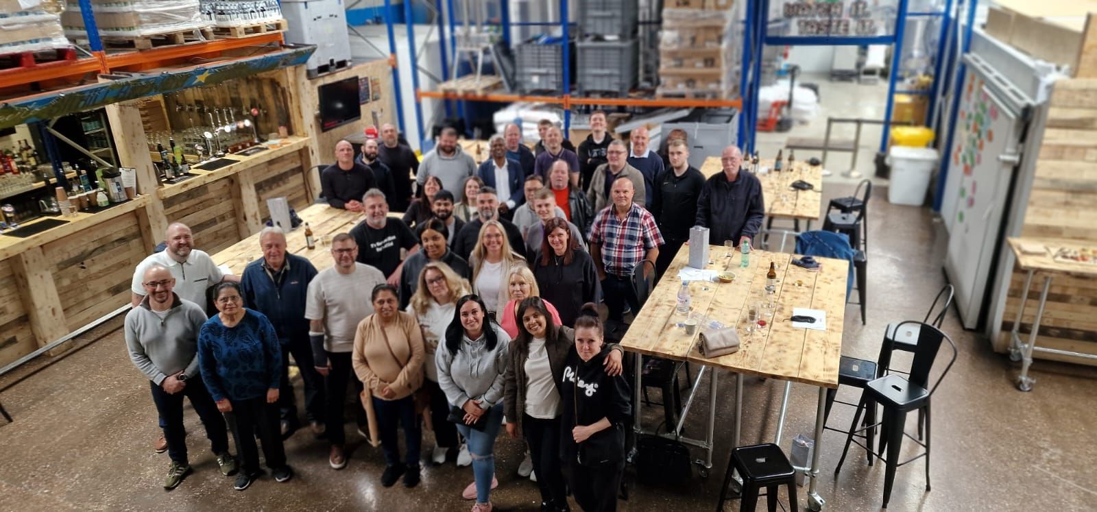 A large group of people are posing for a picture in a warehouse.