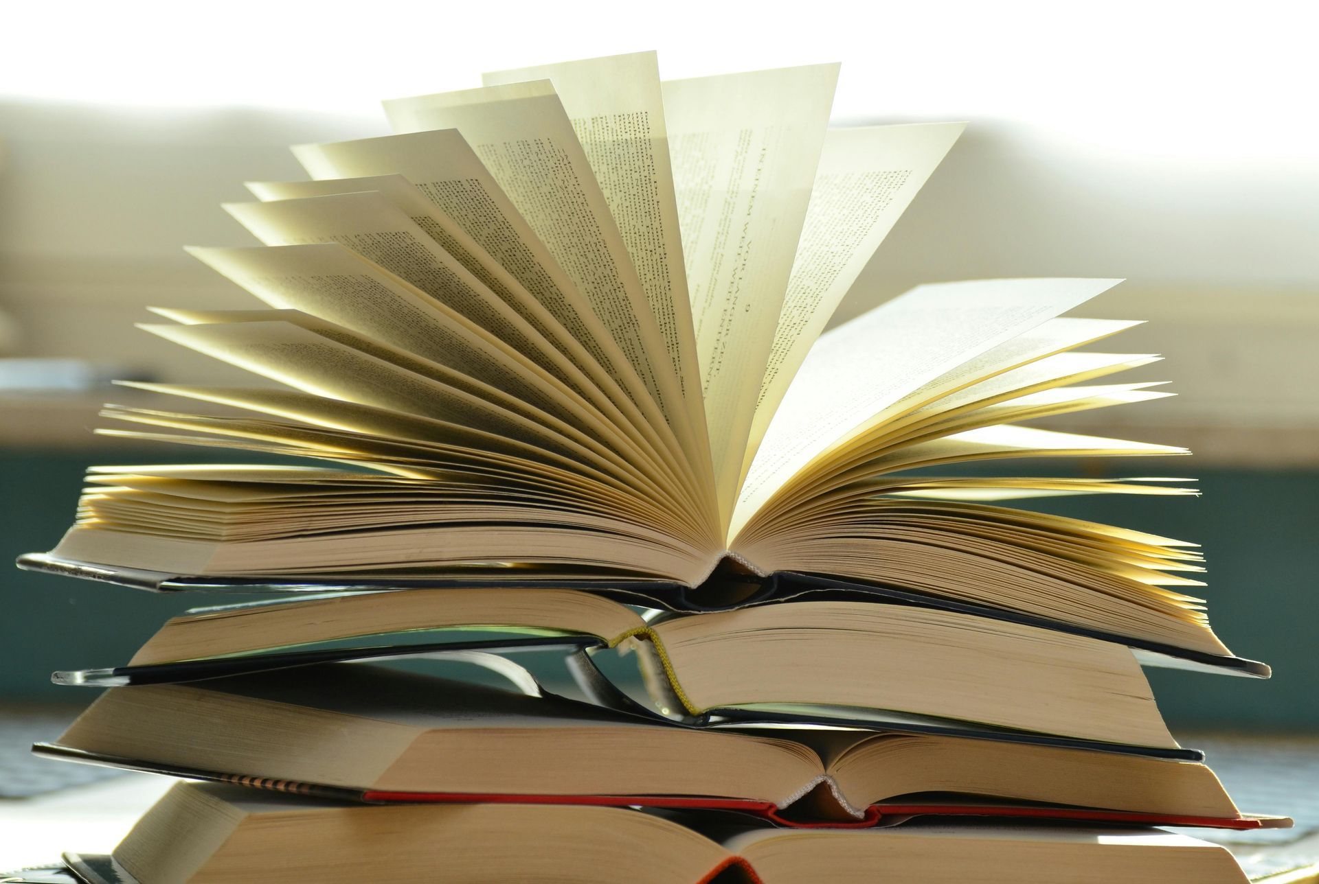 An open book on top of other closed books.