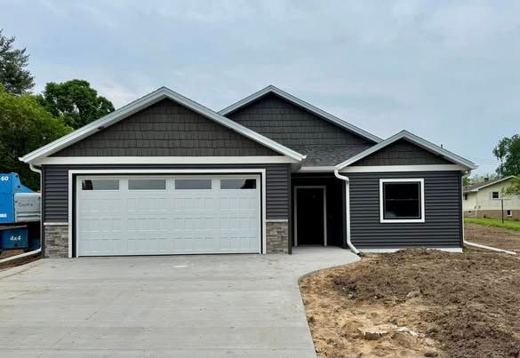 A gray house with a white garage door and a concrete driveway.