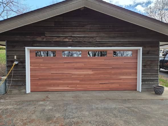 Wooden garage with white trim and closed reddish-brown door on a concrete driveway