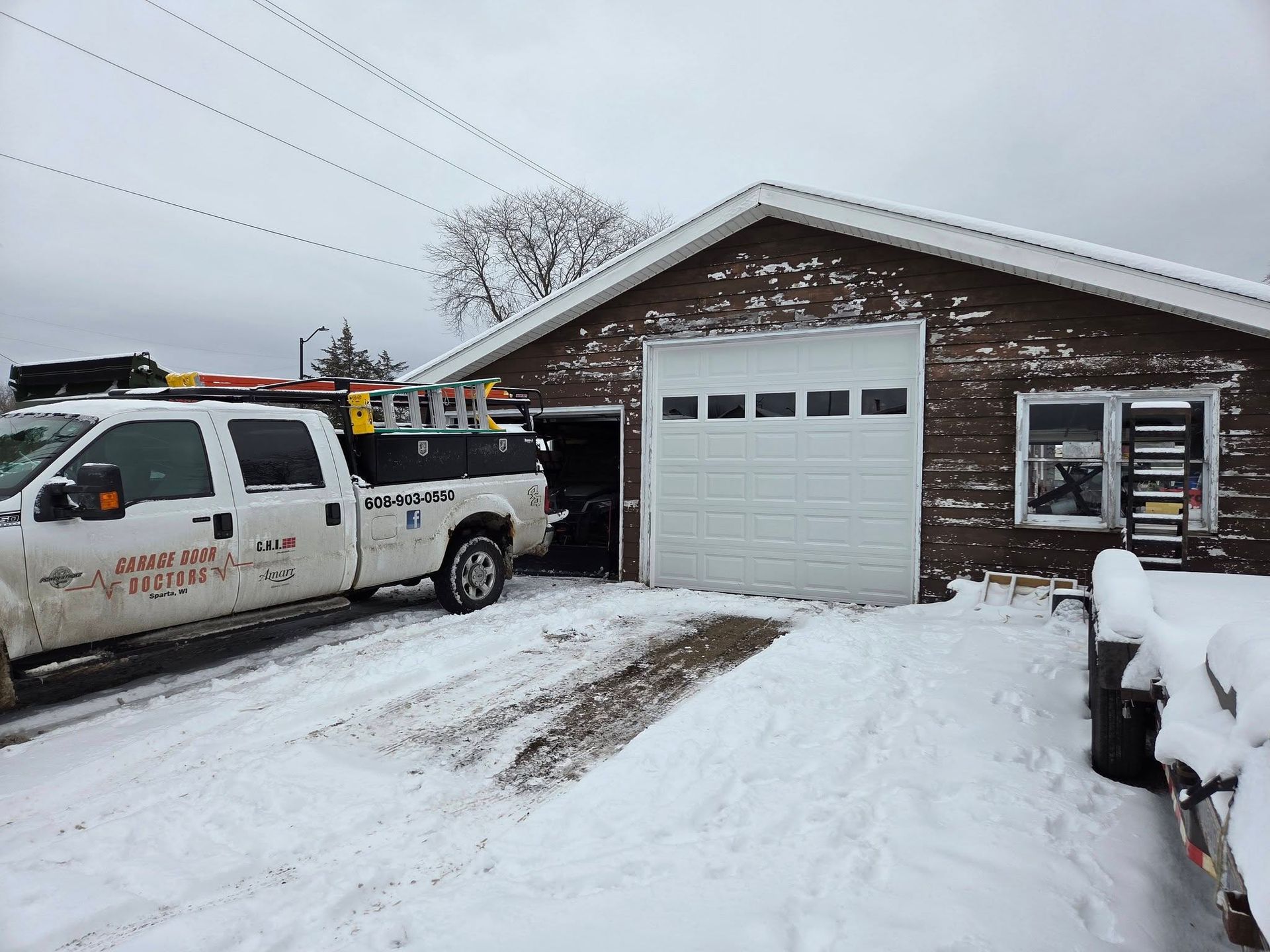 Suburban house with three-car garage, gray siding, and a concrete driveway under cloudy skies