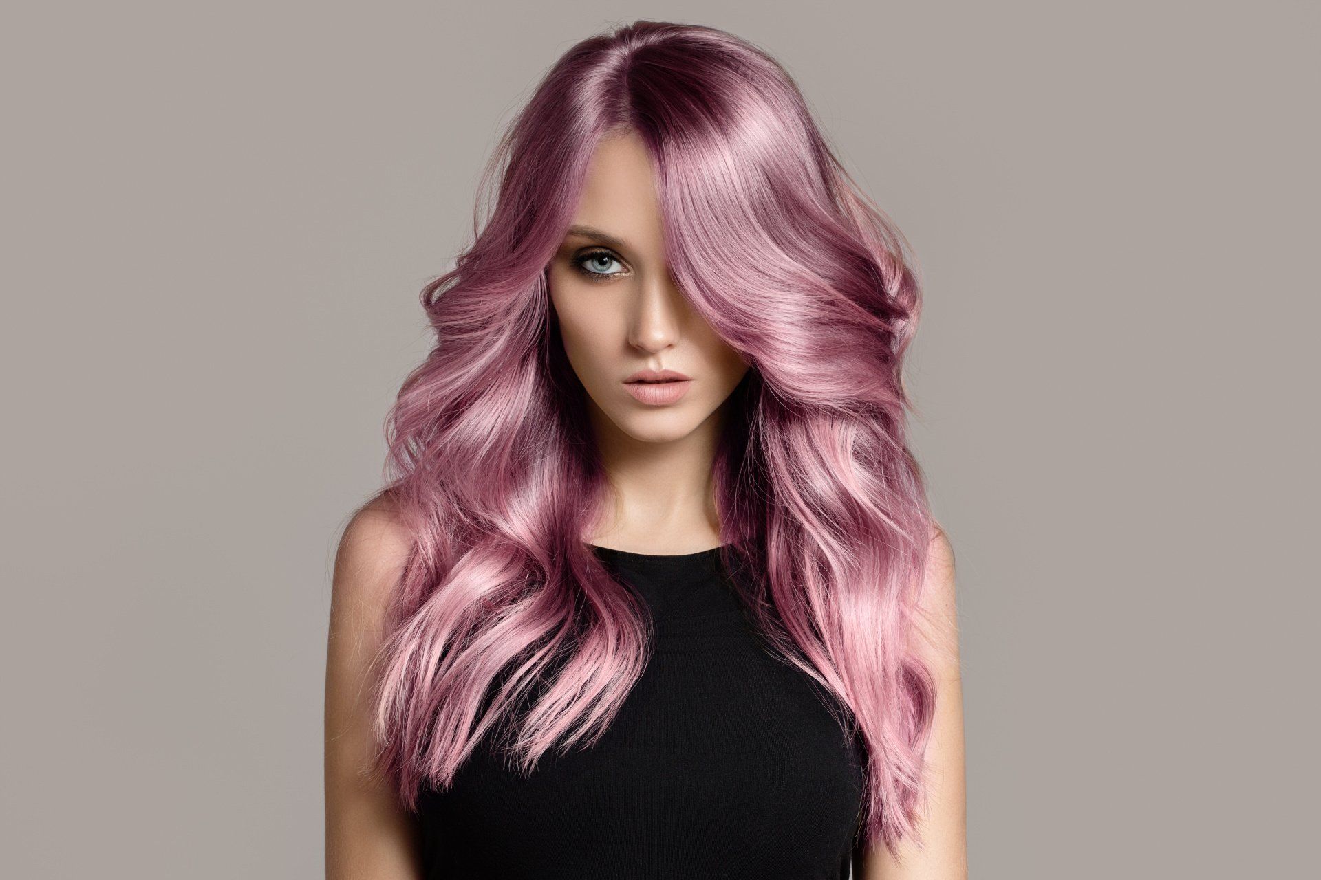 Eine Frau mit langen rosa Haaren trägt ein schwarzes Kleid.