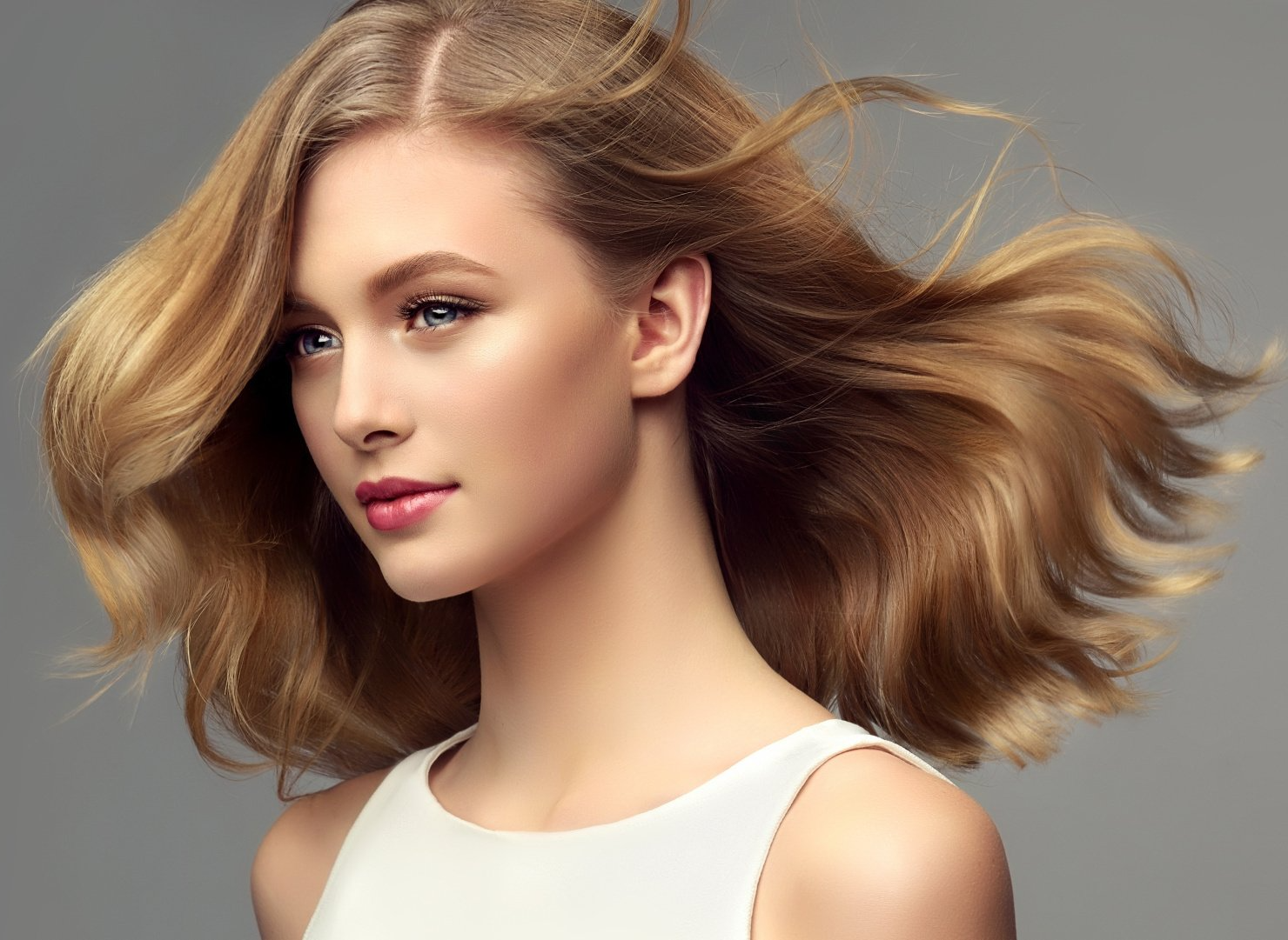 Eine Frau mit langen blonden Haaren trägt ein weißes Tanktop.