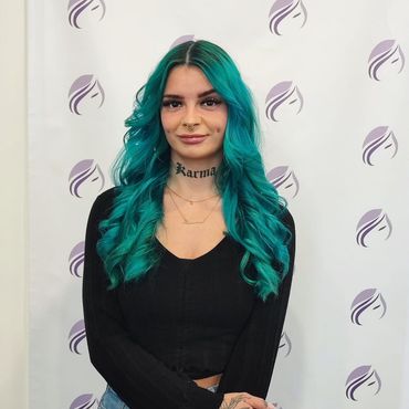 Eine Frau mit grünen Haaren hat ein Tattoo am Hals mit der Aufschrift „Karma“