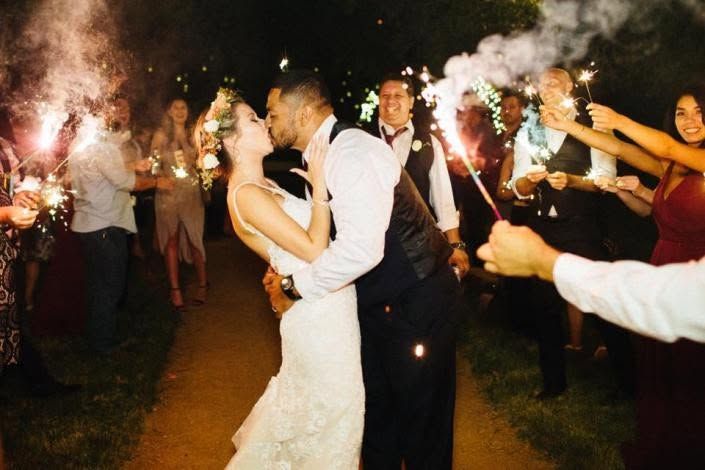 Newlyweds kissing during a sparkler send-off at their nighttime wedding