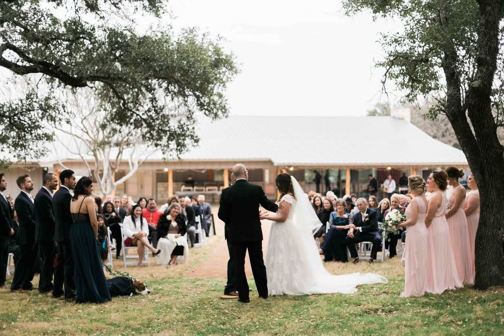 Bride and groom walking hand in hand at an outdoor wedding ceremony with seated guests
