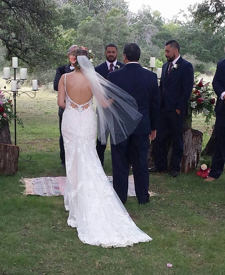 Bride and groom standing at an outdoor wedding ceremony under trees