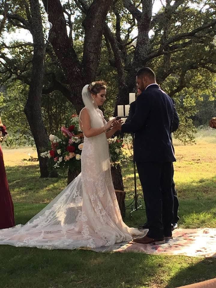 Bride and groom exchanging vows outdoors beneath trees at a wedding ceremony