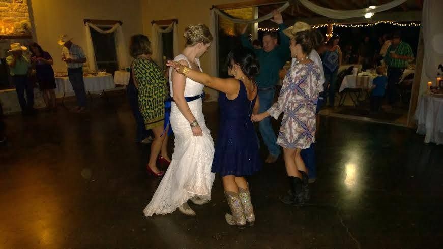 People dancing at a lively indoor party in a room with warm lighting and a stone fireplace.