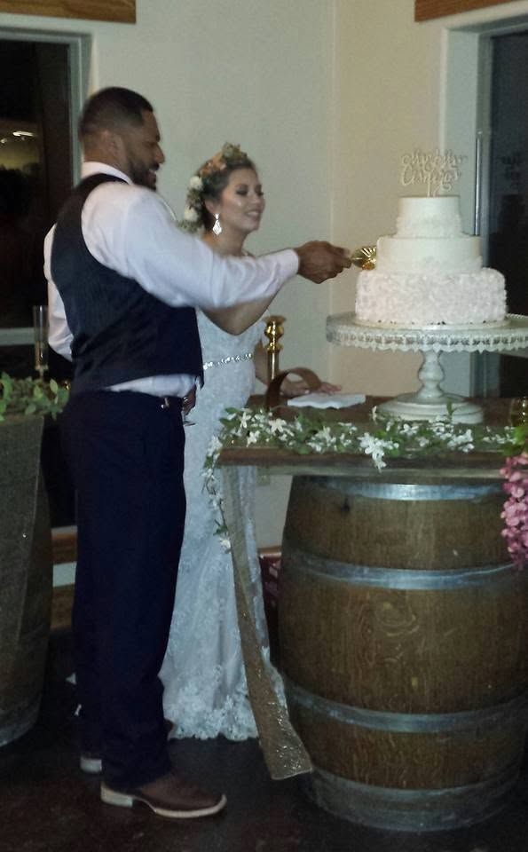 Couple cutting a white tiered wedding cake at a reception table