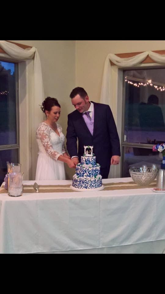 Couple cutting a small white cake at a decorated wedding reception table