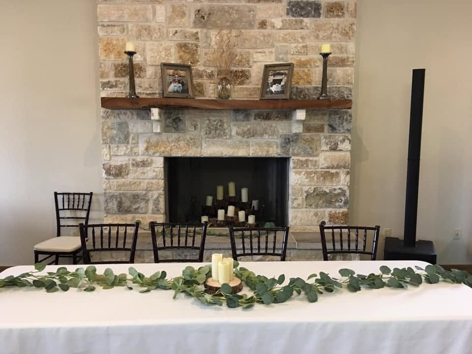 White floral vases and lanterns arranged on a table with greenery garland backdrop