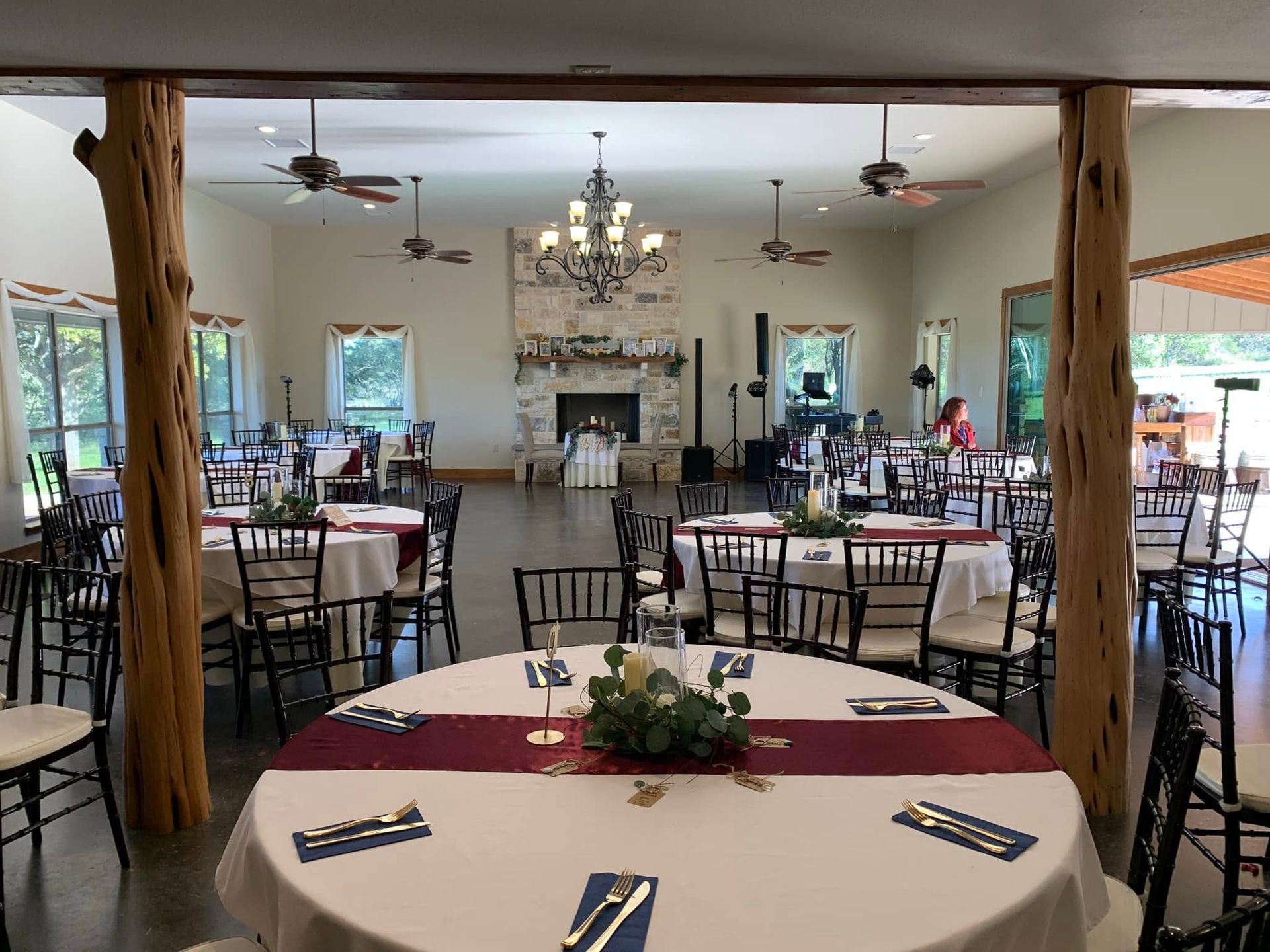 Banquet room with round tables, white tablecloths, and black chairs in a warmly lit dining area
