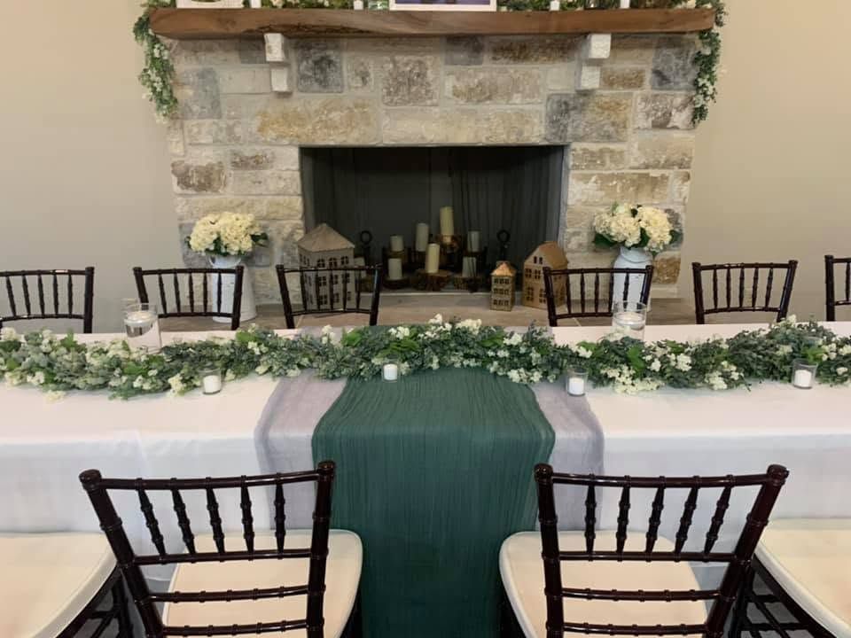 Empty banquet room with round tables, white tablecloths, black chairs, and a wooden support post