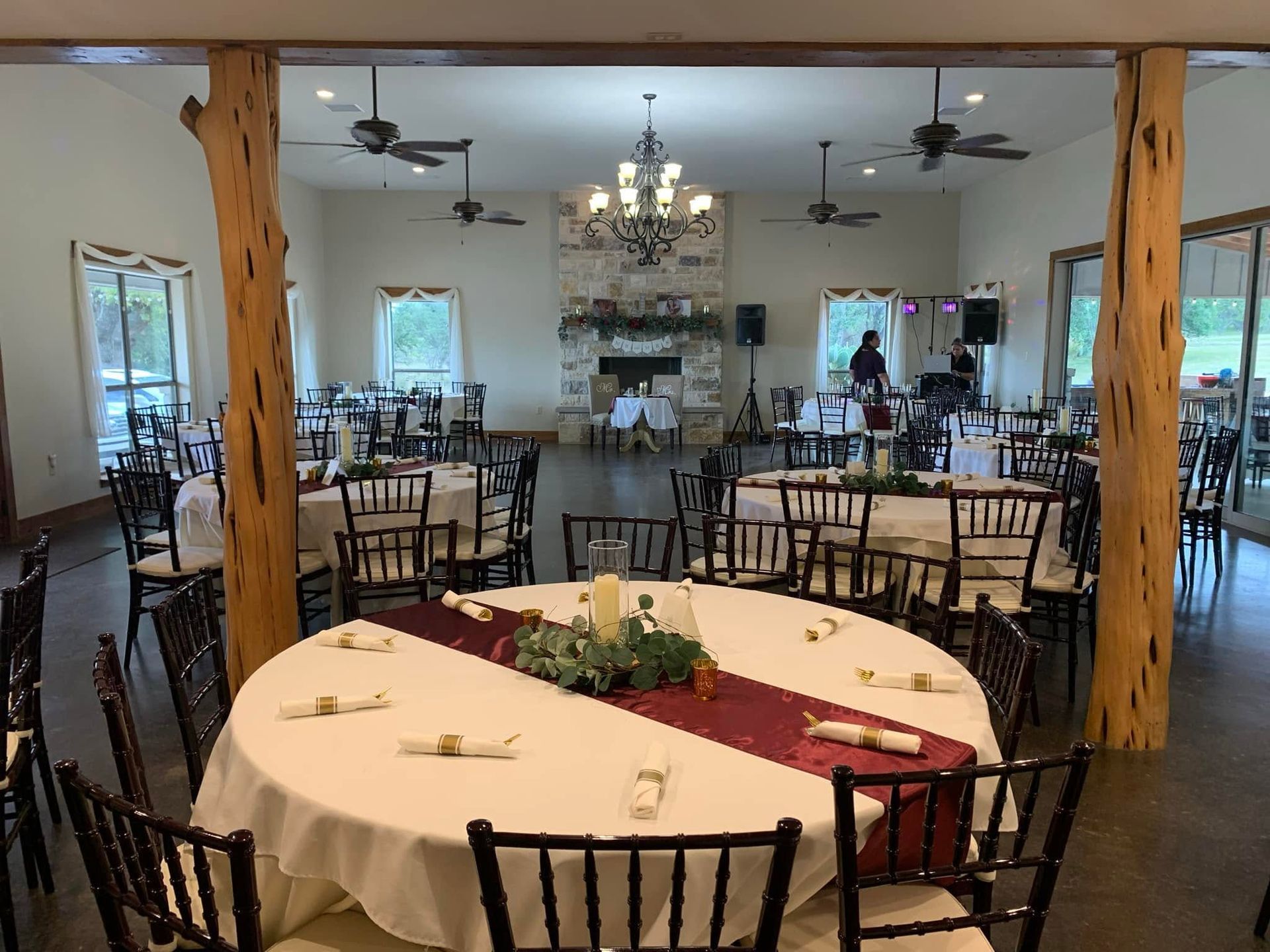 Empty banquet hall with round tables, chairs, chandeliers, and a fireplace