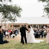 Bride and groom walking down an outdoor aisle with guests seated on both sides