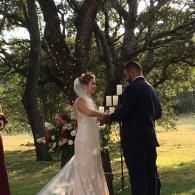 Bride and groom exchanging vows outdoors beneath trees during a wedding ceremony