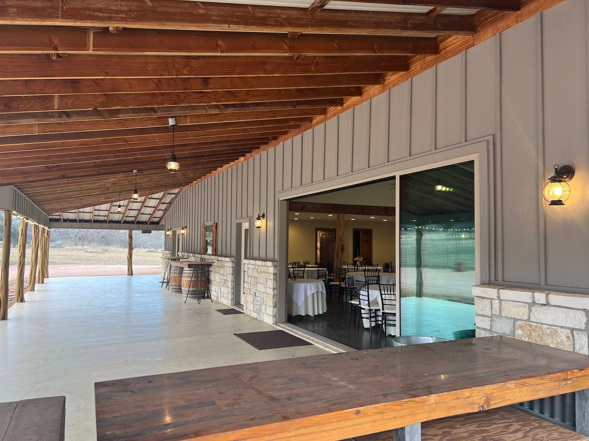 Covered patio with sliding glass doors, ceiling fan, and bar seating overlooking a pool and yard