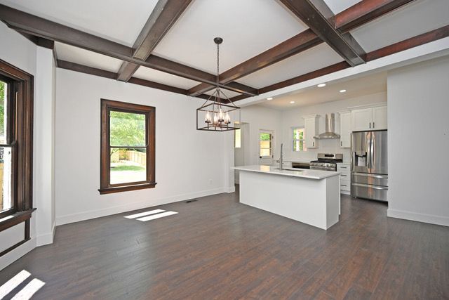 A kitchen and dining room in an empty house with wooden beams