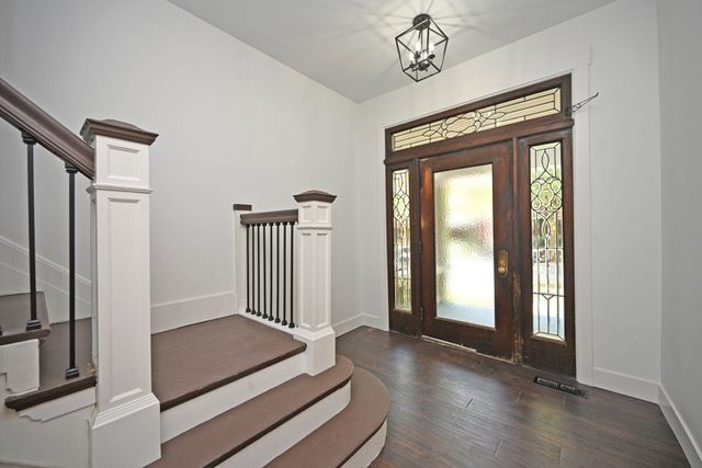 A hallway with stairs leading up to the front door of a house.