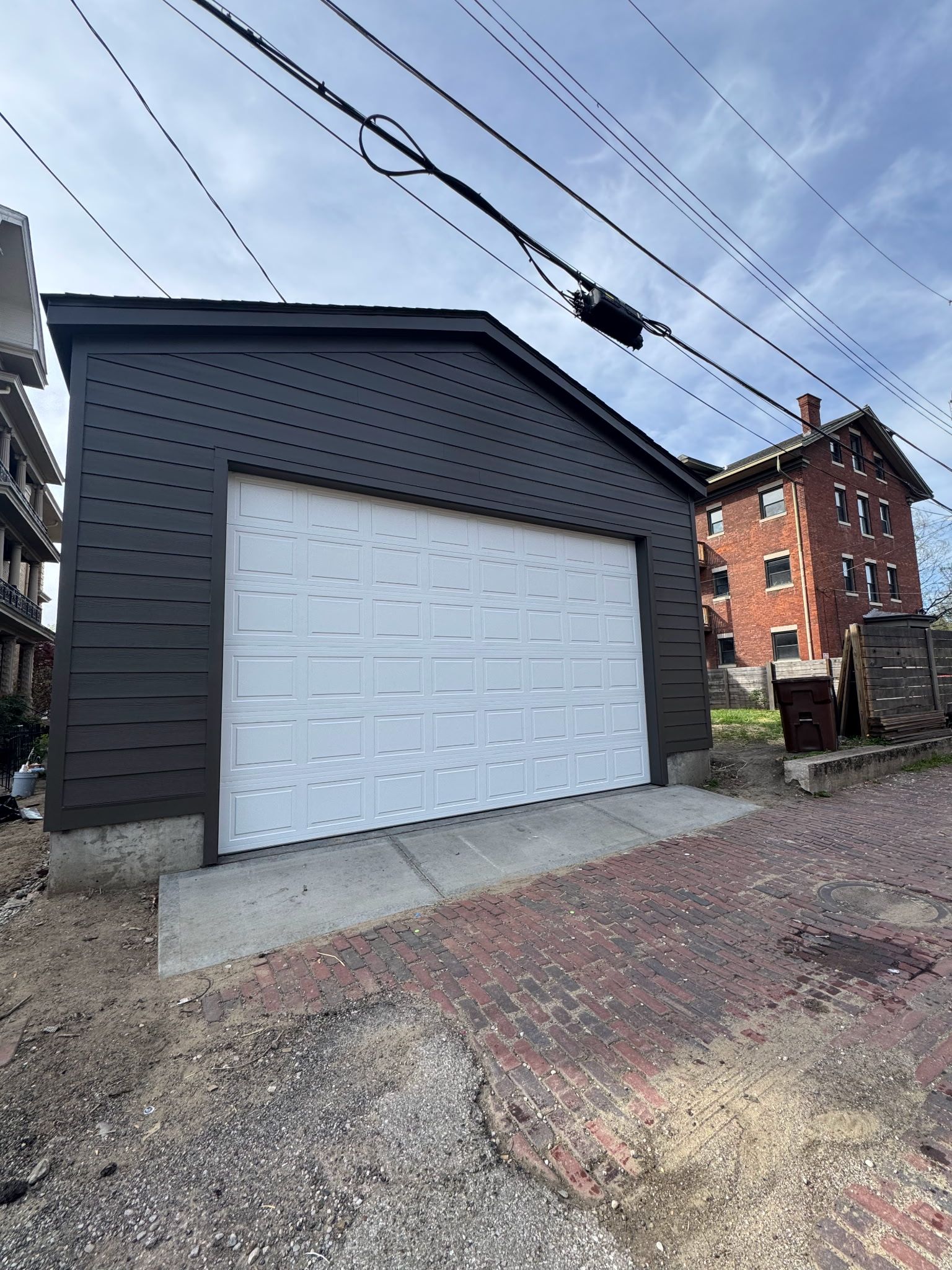 A garage with a white door is sitting next to a brick building.