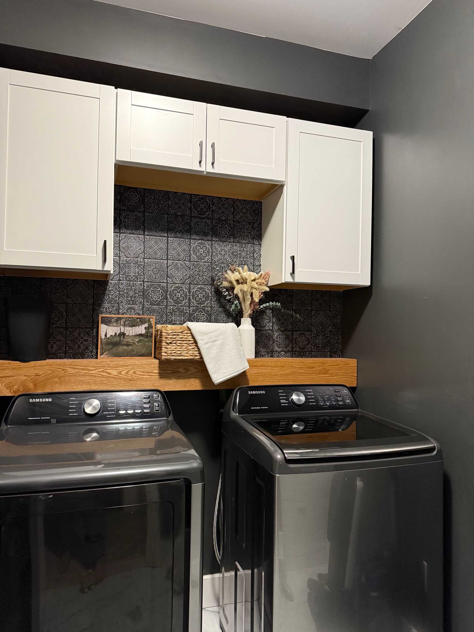 A laundry room with a washer and dryer and white cabinets.