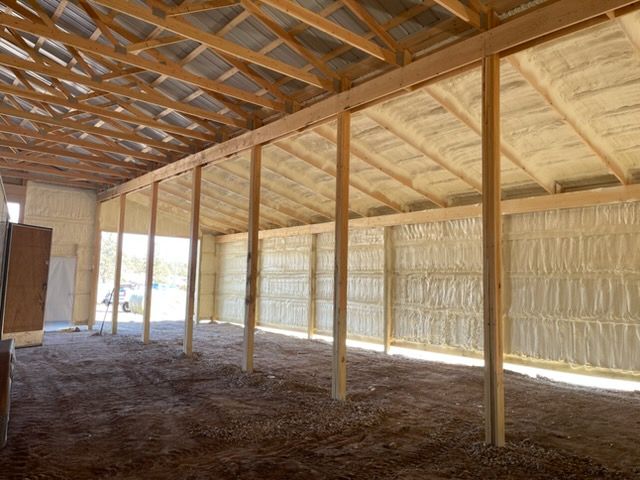 A person applying expanding foam sealant with a gun around a door frame.