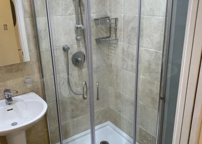 A bathroom with a shower , sink and mirror.