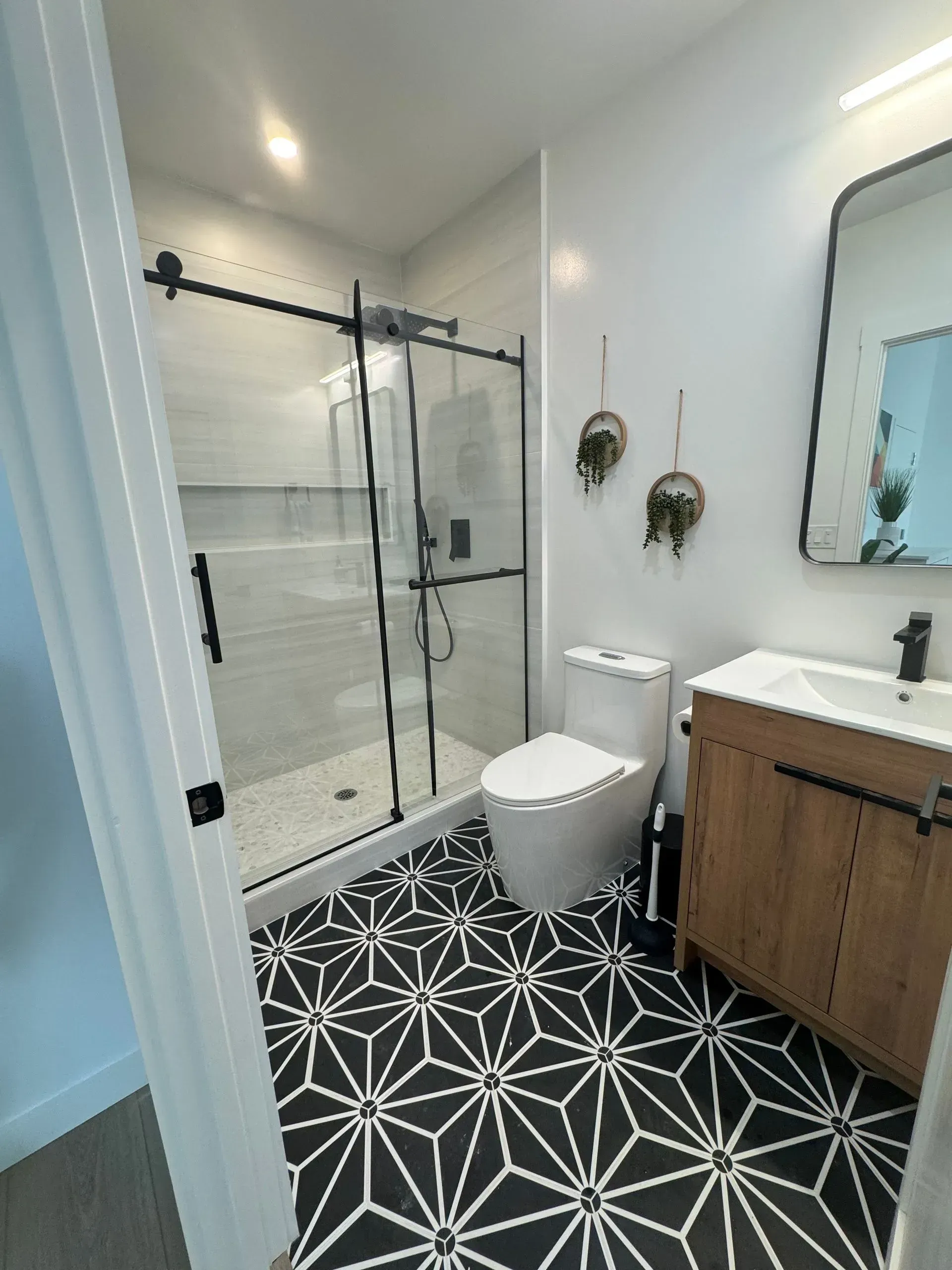 A bathroom with a toilet , sink , shower and mirror.