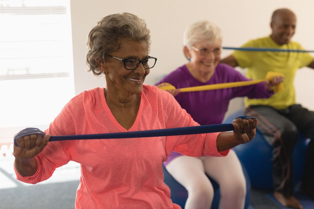 Three People Exercising Indoors Using Resistance Bands — Elevate Injury Management in Sandy Bay, TAS
