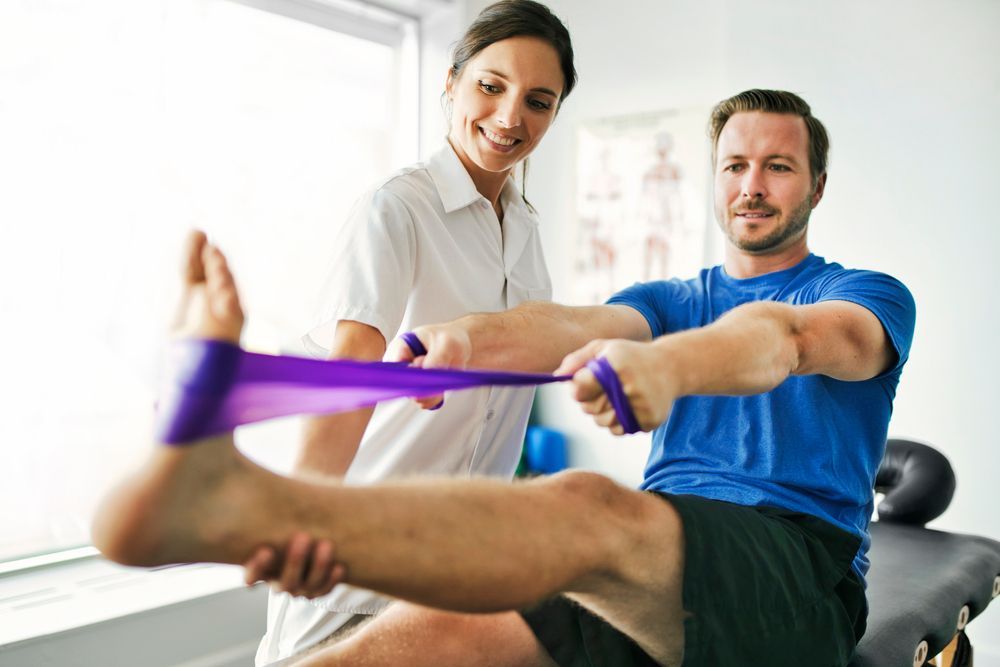 A Physical Therapist Guides a Patient Stretching Their Leg — Elevate Injury Management in Sandy Bay, TAS