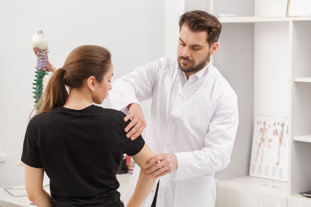 A Clinician in a White Coat Examines a Patient’s Shoulder — Elevate Injury Management in Sandy Bay, TAS
