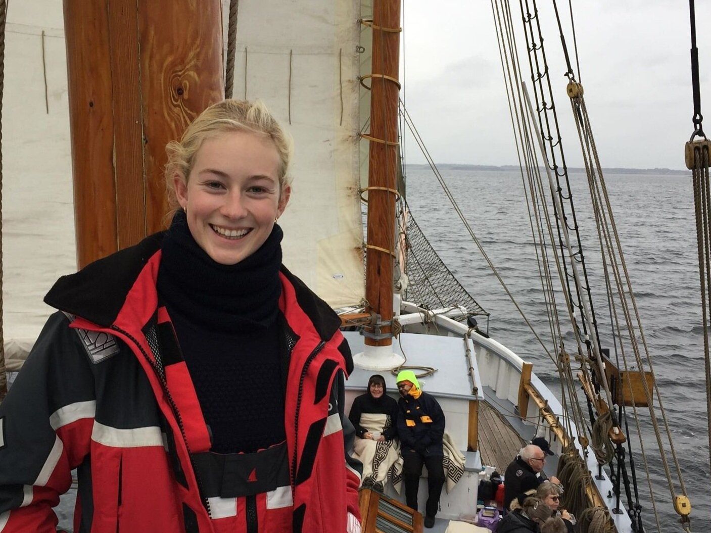 A woman in a red jacket is standing on a boat